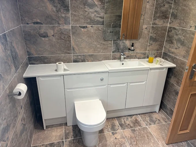 Stone tiled bathroom with fitted vanity unit and WC