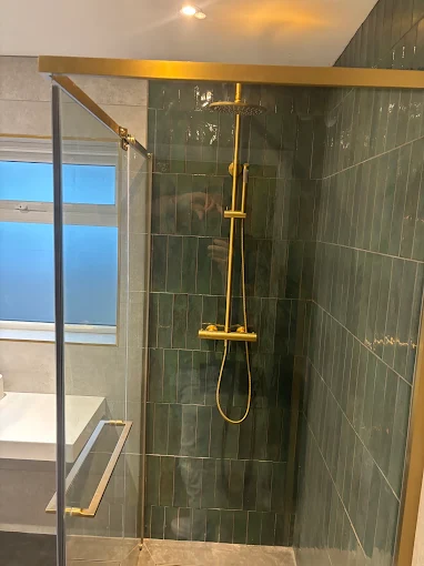 Walk-in shower with green metro tiles and gold shower valve